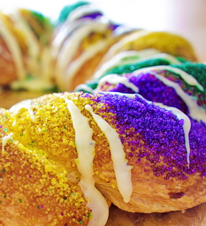 King Cake with frosting drizzle and purple, yellow and green sugar granules on top