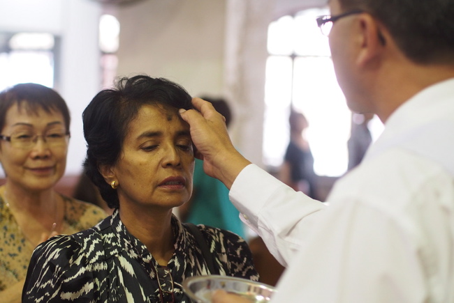 Man putting ashes on woman's forehead