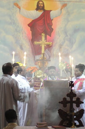 Priests with candles with painting of Jesus ascending in background