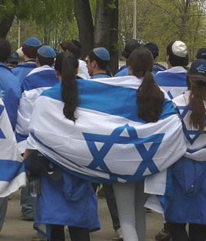 People walking with Israeli flags wrapped around them, in group