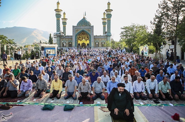 Group of Muslims kneeling in prayer, daytime, outdoors