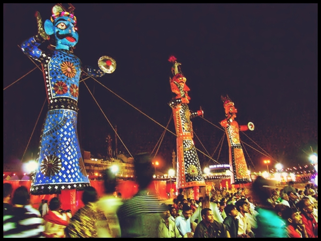 Tall colorful effigies in night with crowd