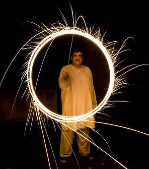 Man in white Indian tunic making circle of light with sparkler firecracker