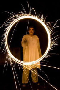 Man in white Indian tunic making circle of light with sparkler firecracker
