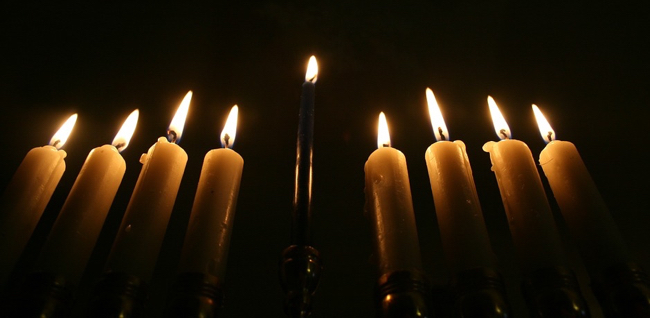 Nine lit candles on a menorah, close-up from low perspective