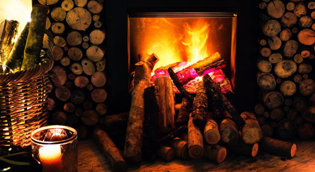Fireplace lit with fire, logs all around