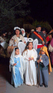 Children and adults in group on street at night costumed as angels and other nativity figures