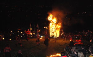 Fire with dancers in middle of crowd, nighttime