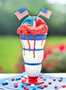 Red, white and blue frozen dessert in cup with American flags on top