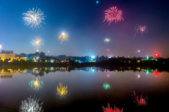 Dark night sky, dusk, colorful fireworks over body of water