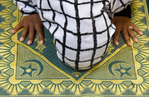 Woman in hijab on prayer rug, head down